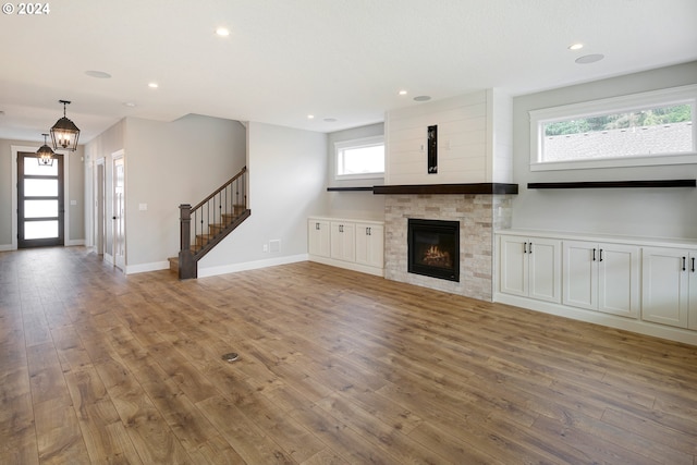 unfurnished living room featuring a healthy amount of sunlight, hardwood / wood-style flooring, and an inviting chandelier