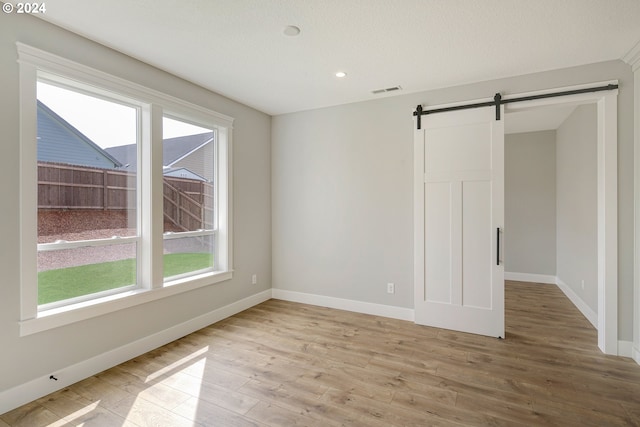 spare room featuring a barn door and light wood-type flooring