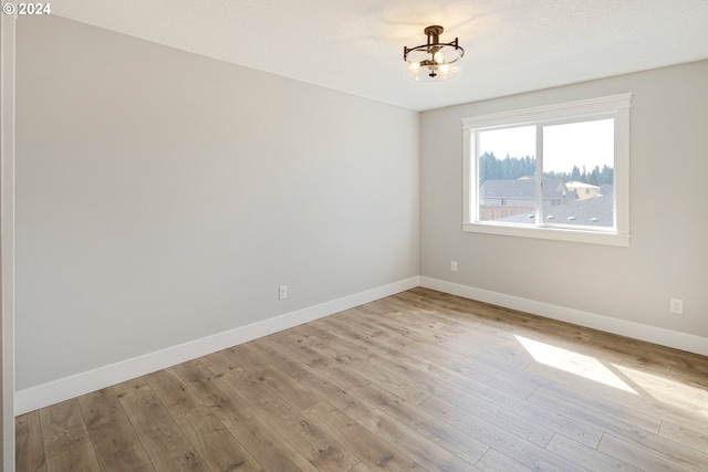 empty room featuring an inviting chandelier and light hardwood / wood-style flooring