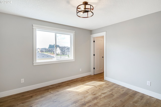 unfurnished room with light hardwood / wood-style flooring and a textured ceiling