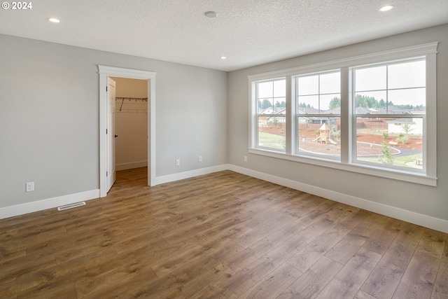 empty room with a textured ceiling and hardwood / wood-style flooring