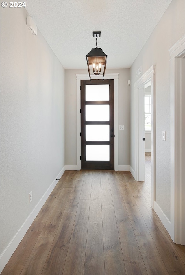 doorway to outside with hardwood / wood-style flooring and a chandelier