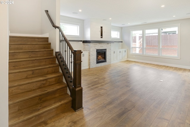 unfurnished living room featuring hardwood / wood-style flooring, a tile fireplace, and a wealth of natural light