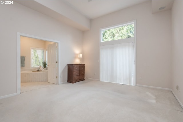 unfurnished bedroom featuring light colored carpet and ensuite bath