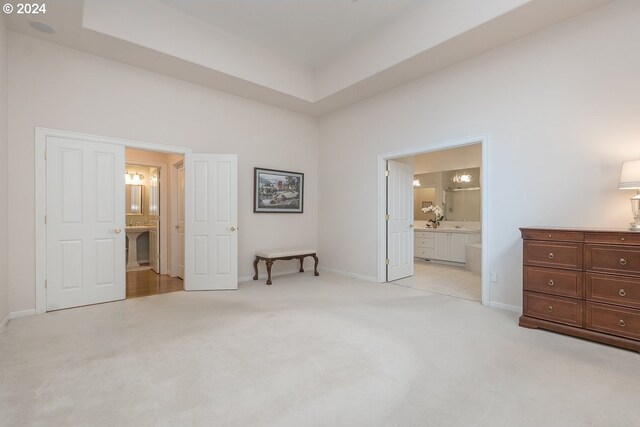 bedroom featuring connected bathroom and light carpet