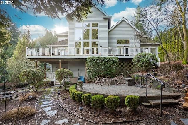 back of property with a fire pit, a patio area, and a deck