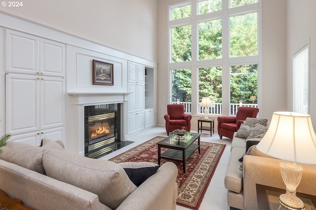 living room featuring a wealth of natural light, a fireplace, and a high ceiling