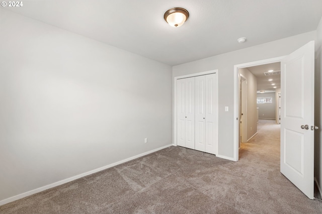 unfurnished bedroom with light carpet and a closet