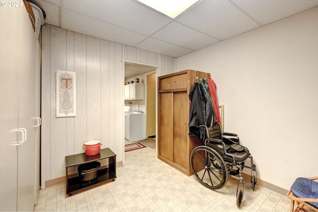 interior space with wood walls, light tile floors, a paneled ceiling, and washer and clothes dryer