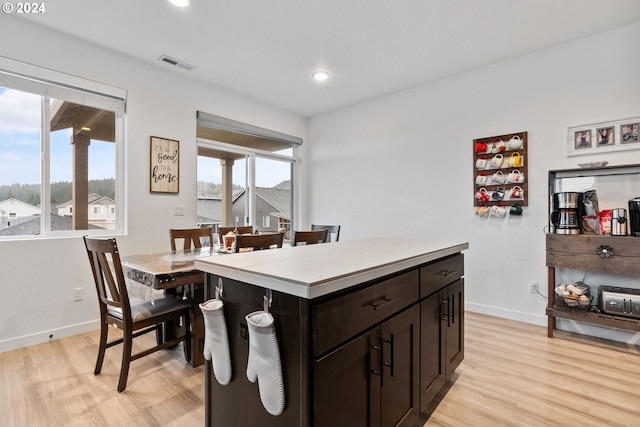 kitchen with dark brown cabinets, light wood-type flooring, and a kitchen island