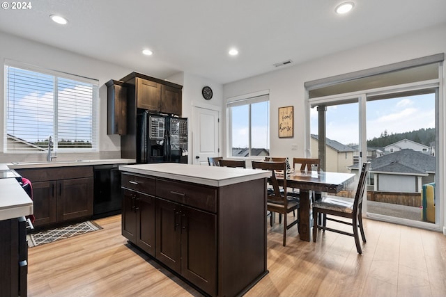 kitchen featuring a center island, black appliances, sink, light hardwood / wood-style flooring, and dark brown cabinets