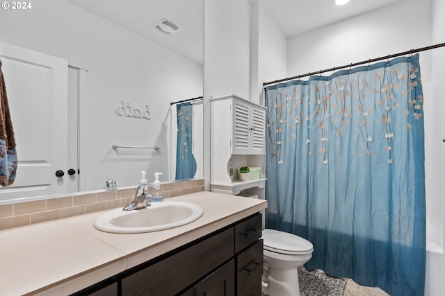 bathroom featuring toilet, vanity, tasteful backsplash, and shower / bath combo with shower curtain