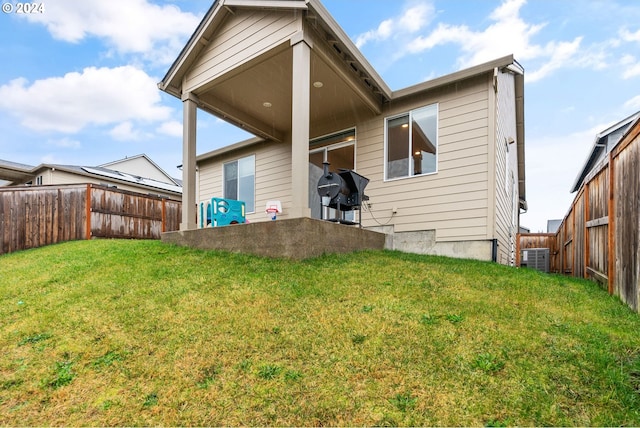 rear view of house featuring cooling unit and a yard