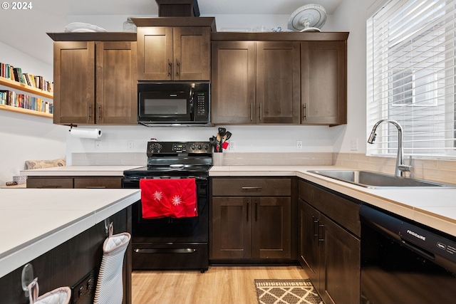 kitchen with black appliances, dark brown cabinets, sink, and light hardwood / wood-style flooring