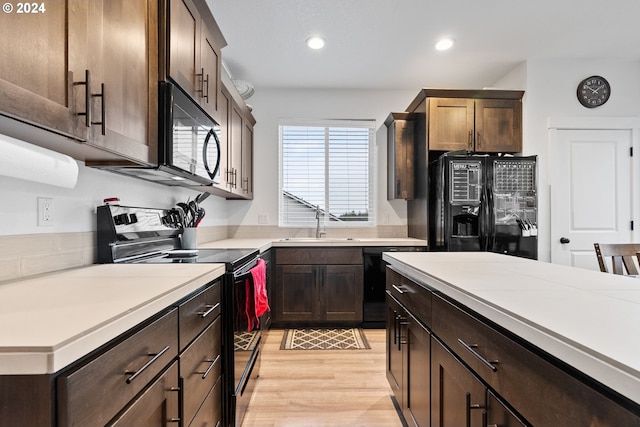 kitchen featuring black appliances, dark brown cabinets, light wood-type flooring, and sink