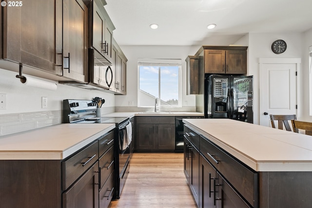 kitchen with black appliances, a sink, dark brown cabinets, light countertops, and recessed lighting
