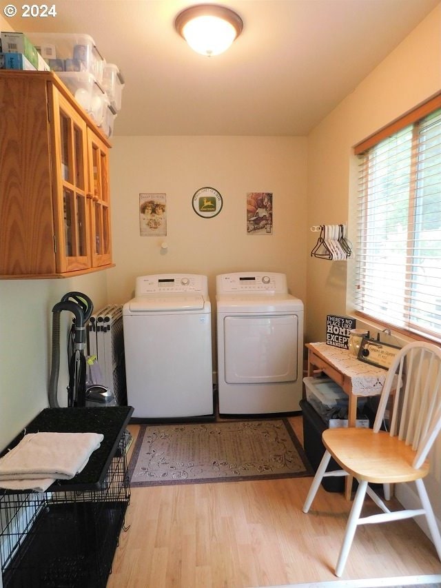 clothes washing area featuring washer and clothes dryer, light hardwood / wood-style flooring, and radiator heating unit