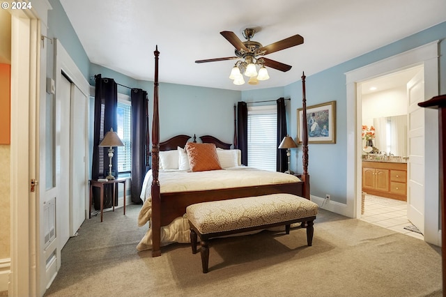 carpeted bedroom with multiple windows, baseboards, a ceiling fan, and ensuite bathroom