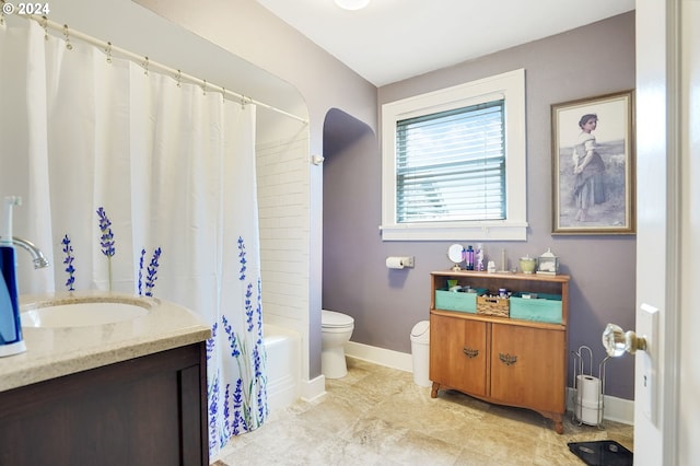 bathroom with baseboards, vanity, toilet, and shower / bath combo with shower curtain