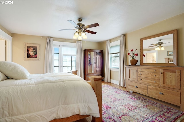 bedroom with baseboards, a ceiling fan, and light wood-style floors