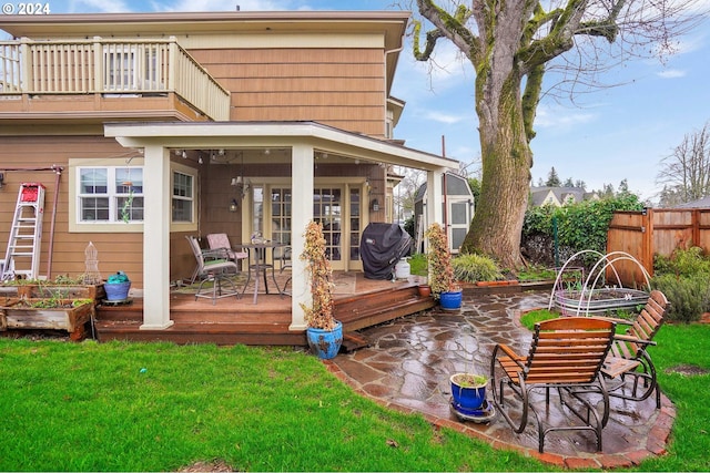 back of house featuring a balcony, fence, and a yard