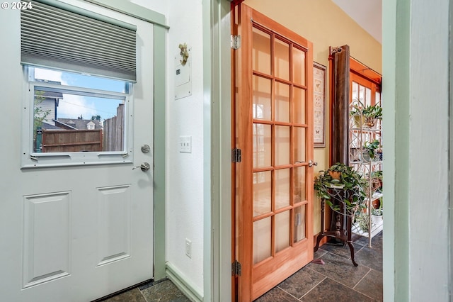 doorway with baseboards, a wealth of natural light, and stone tile floors