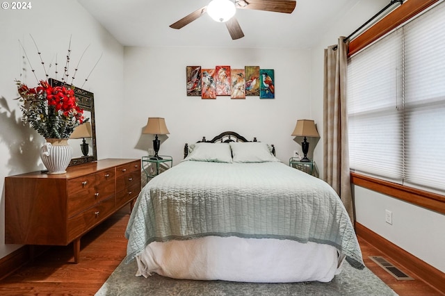 bedroom with ceiling fan, wood finished floors, visible vents, and baseboards