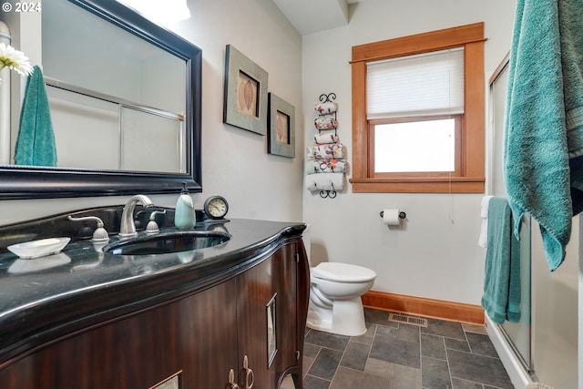 full bath featuring a stall shower, baseboards, visible vents, stone finish flooring, and vanity