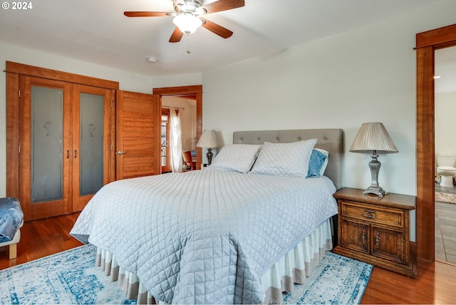 bedroom with ceiling fan, ensuite bath, and wood finished floors