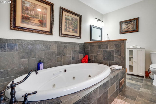 bathroom featuring stone finish floor, toilet, and a tub with jets