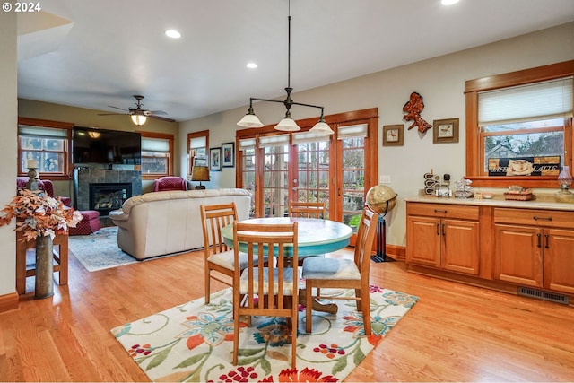 dining space featuring a tile fireplace, recessed lighting, visible vents, light wood-style floors, and french doors