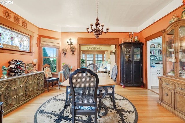 dining area featuring light wood-style floors, a chandelier, and french doors