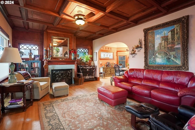 living room with a wealth of natural light, arched walkways, coffered ceiling, and wood finished floors