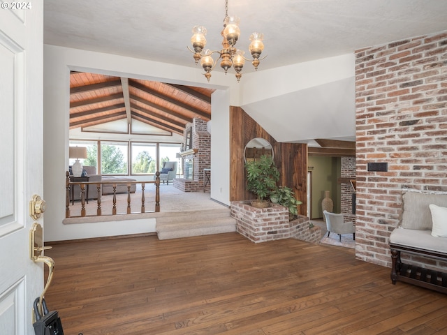 foyer entrance with lofted ceiling with beams, an inviting chandelier, a fireplace, and hardwood / wood-style floors