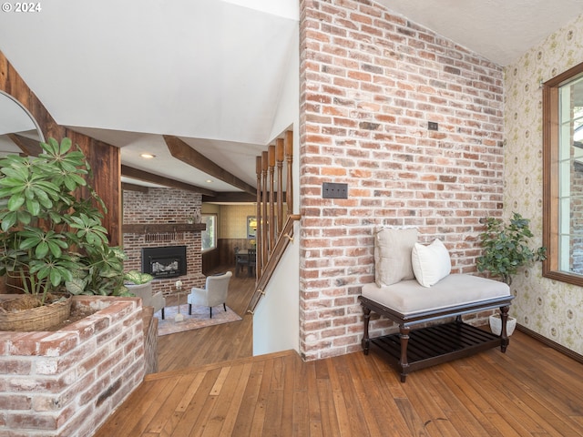 foyer featuring baseboards, hardwood / wood-style floors, a fireplace, and wallpapered walls