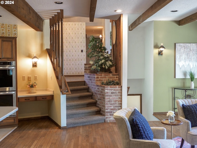 stairs with wood-type flooring, beamed ceiling, a textured ceiling, and baseboards