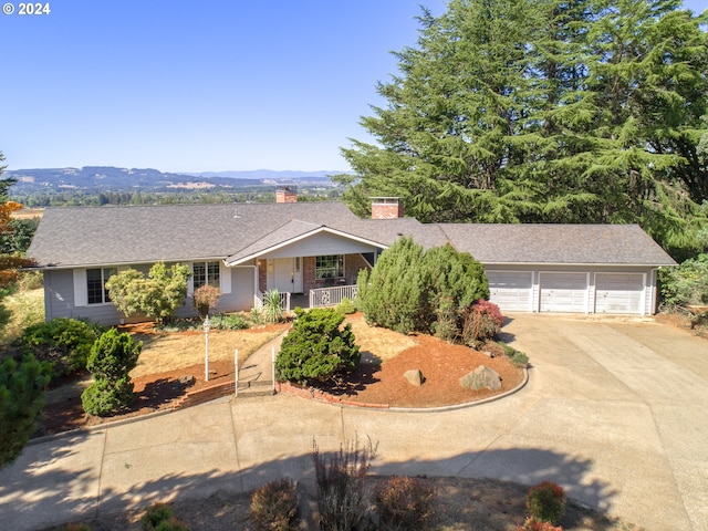 single story home with covered porch, concrete driveway, a shingled roof, and a chimney