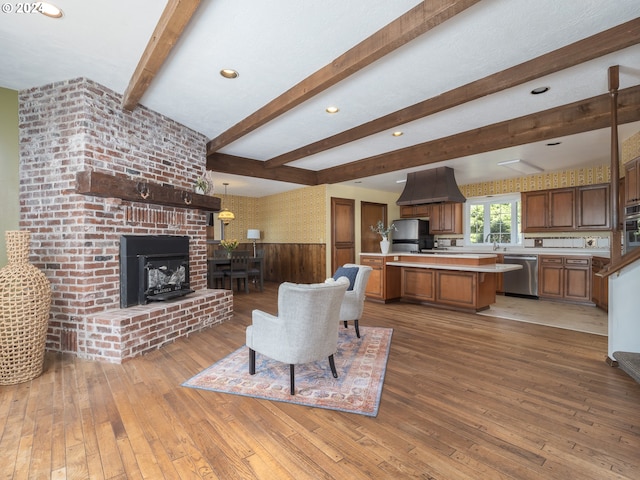 living area with recessed lighting, beam ceiling, a wainscoted wall, and light wood-style flooring