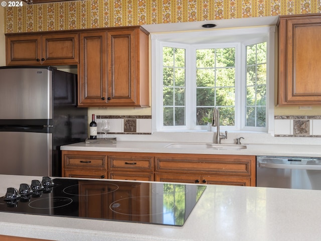 kitchen with tasteful backsplash, brown cabinetry, appliances with stainless steel finishes, light countertops, and a sink