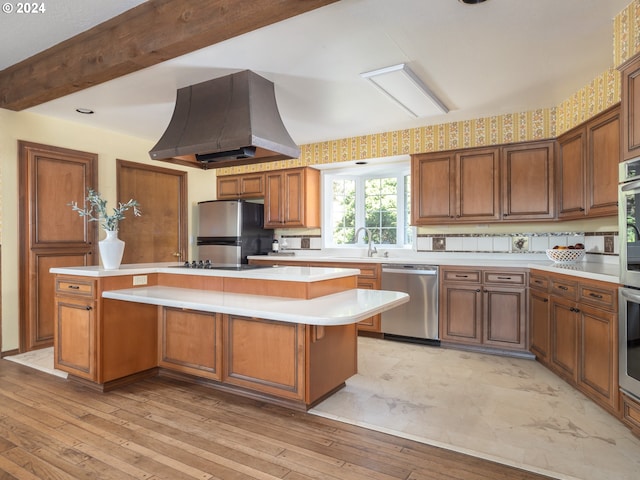 kitchen with brown cabinets, stainless steel appliances, light countertops, a kitchen island, and island range hood