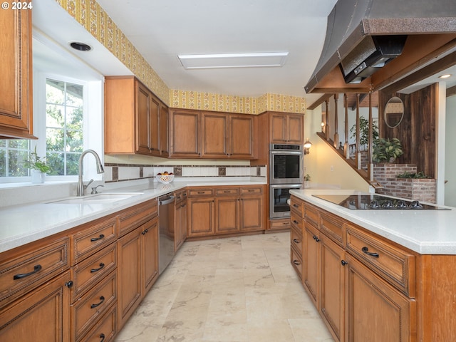 kitchen with range hood, appliances with stainless steel finishes, a sink, and brown cabinets