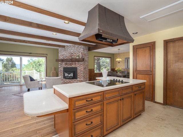 kitchen with black electric cooktop, island range hood, open floor plan, light countertops, and brown cabinets