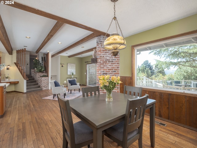 dining area with visible vents, wainscoting, hardwood / wood-style floors, beamed ceiling, and stairs