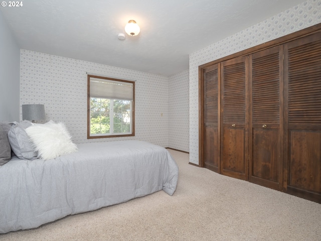 carpeted bedroom featuring wallpapered walls and a closet