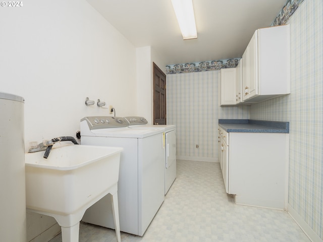 washroom featuring a sink, cabinet space, light floors, washer and clothes dryer, and wallpapered walls