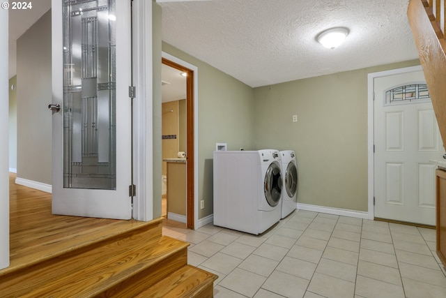 laundry room with washer and dryer, light tile patterned floors, and a textured ceiling