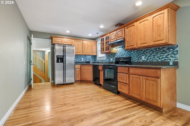 kitchen with decorative backsplash, light wood-type flooring, and black appliances