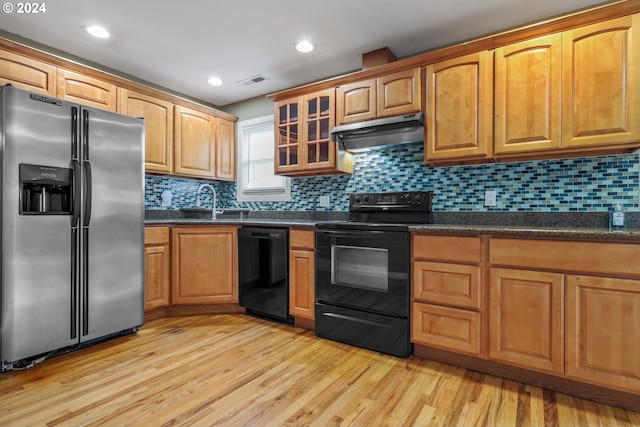 kitchen with decorative backsplash, light wood-type flooring, range hood, and black appliances