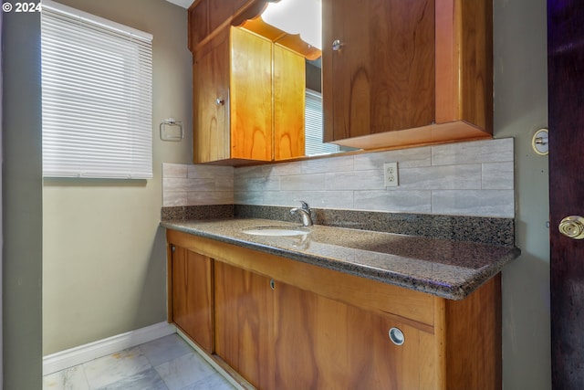 kitchen with backsplash, dark stone countertops, and sink