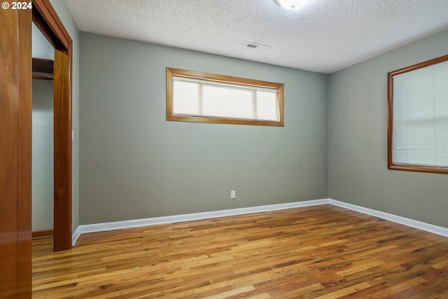 spare room with a textured ceiling and light hardwood / wood-style flooring